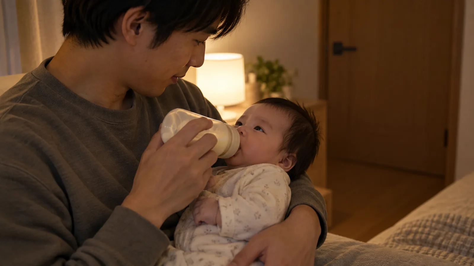 夜中に赤ちゃんを抱っこして授乳する父親